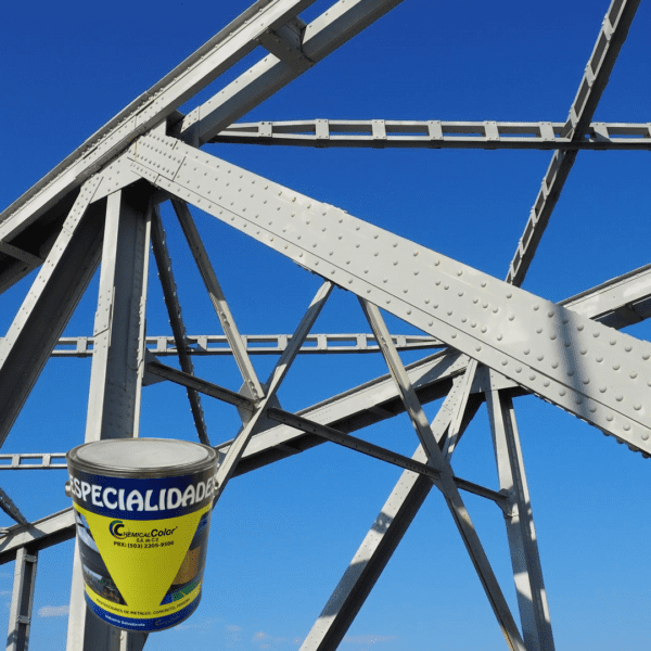 Galón de pintura de la línea Especialidades de Chemical Color de Megacolor frente a una estructura de acero de puente bajo un cielo azul despejado, resaltando su uso en proyectos de construcción e infraestructura.
